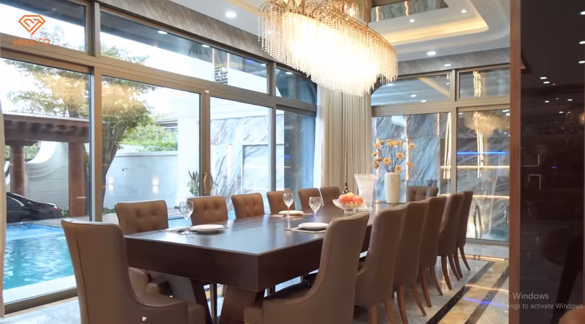 Bàn ăn lớn cũng làm bằng gỗ hương liền khối, có tầm nhìn hướng ra bể bơi.