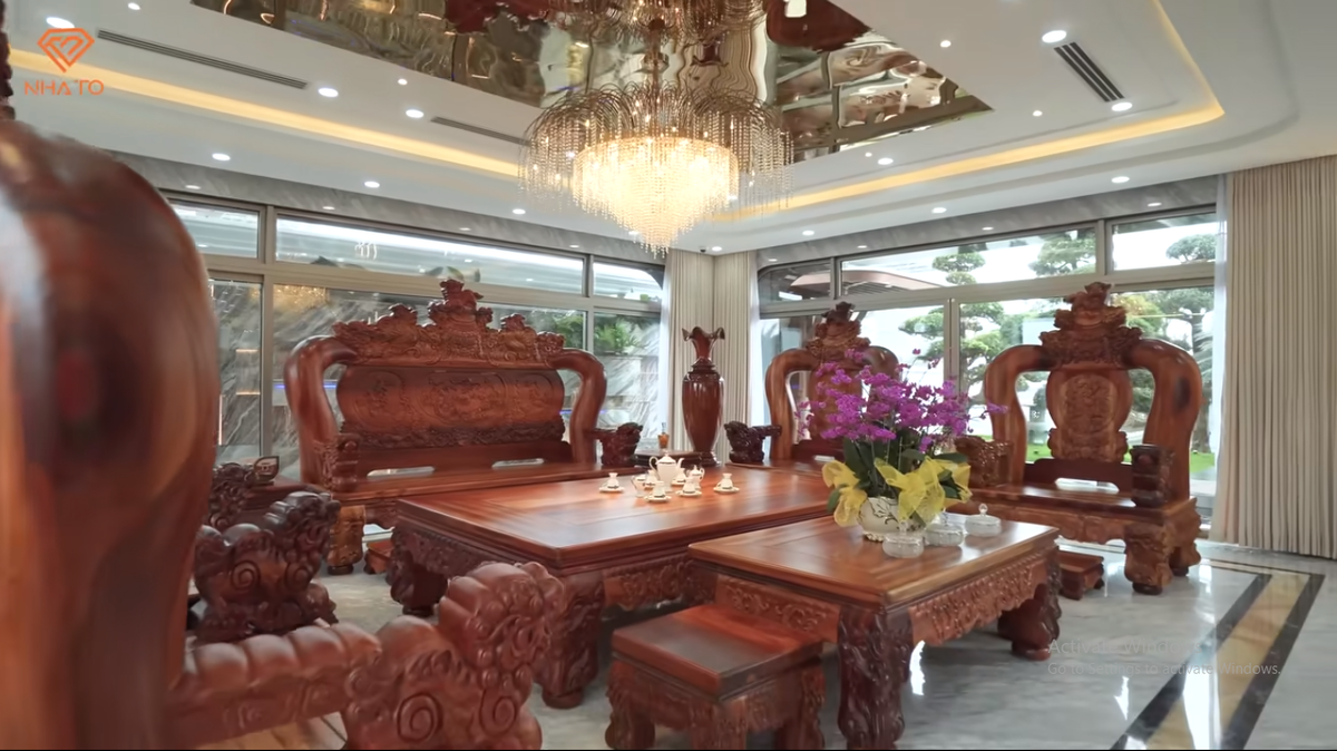 Trong phòng khách đặt bộ bàn ghế bằng gỗ hương nguyên khối lớn.