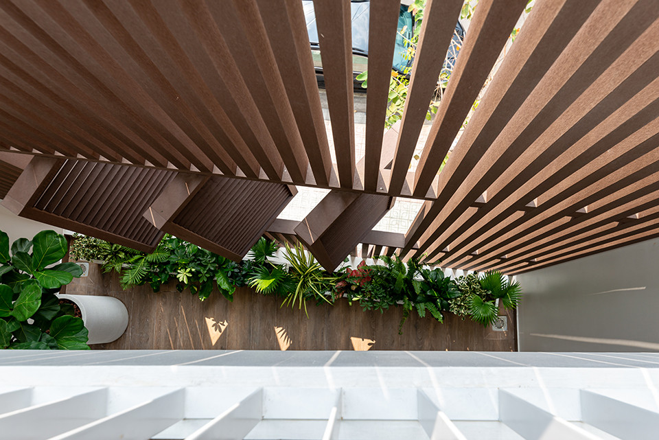 Phía sau lớp lam chắn là bồn cây tươi tắn, đóng vai trò như lớp lọc tự nhiên cho căn nhà. 