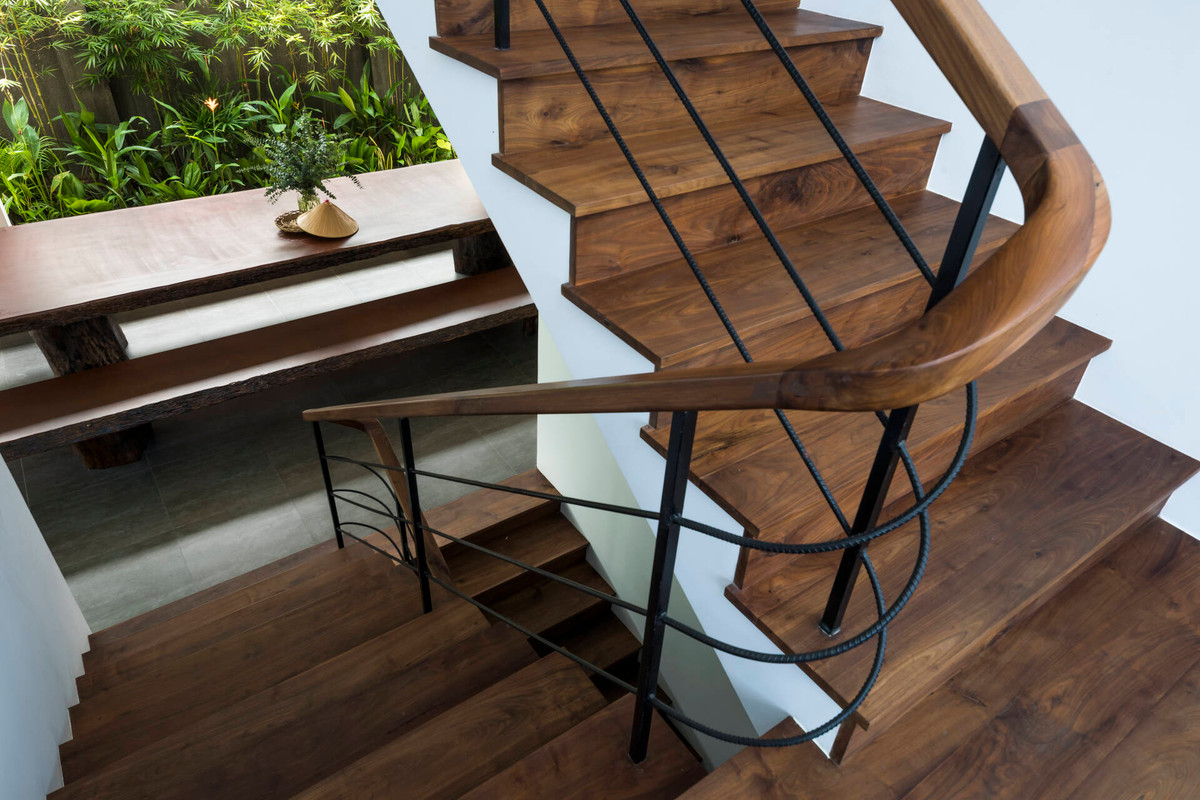 Cầu thang dẫn lên các tầng là sự kết hợp của gỗ nâu tự nhiên và lan can là thép uốn cong.