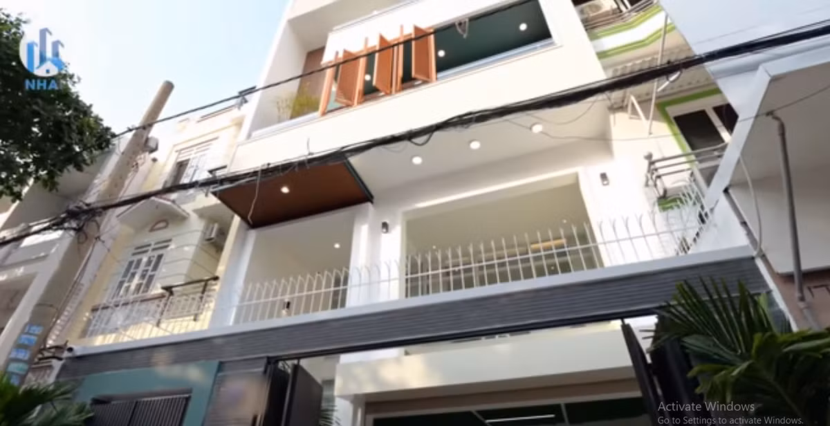 Bên ngoài căn nhà sơn màu trắng chủ đạo và ốp một chút gạch tạo điểm nhấn. Ảnh chụp màn hình NhaF