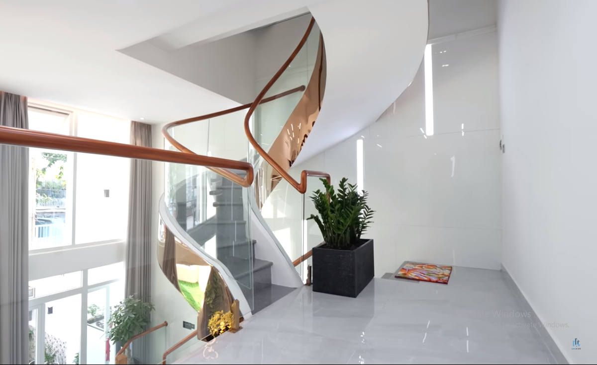 Cầu thang bộ giống như một chi tiết trang trí cho không gian thông tầng. Thành cầu thang được ốp inox vàng hồng. Ảnh chụp màn hình NhaF