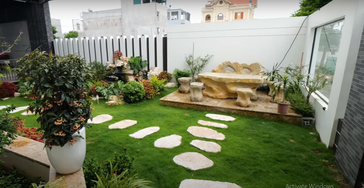 Một bên là khu vườn với lối đi được lát đá và thảm cỏ xanh mướt.