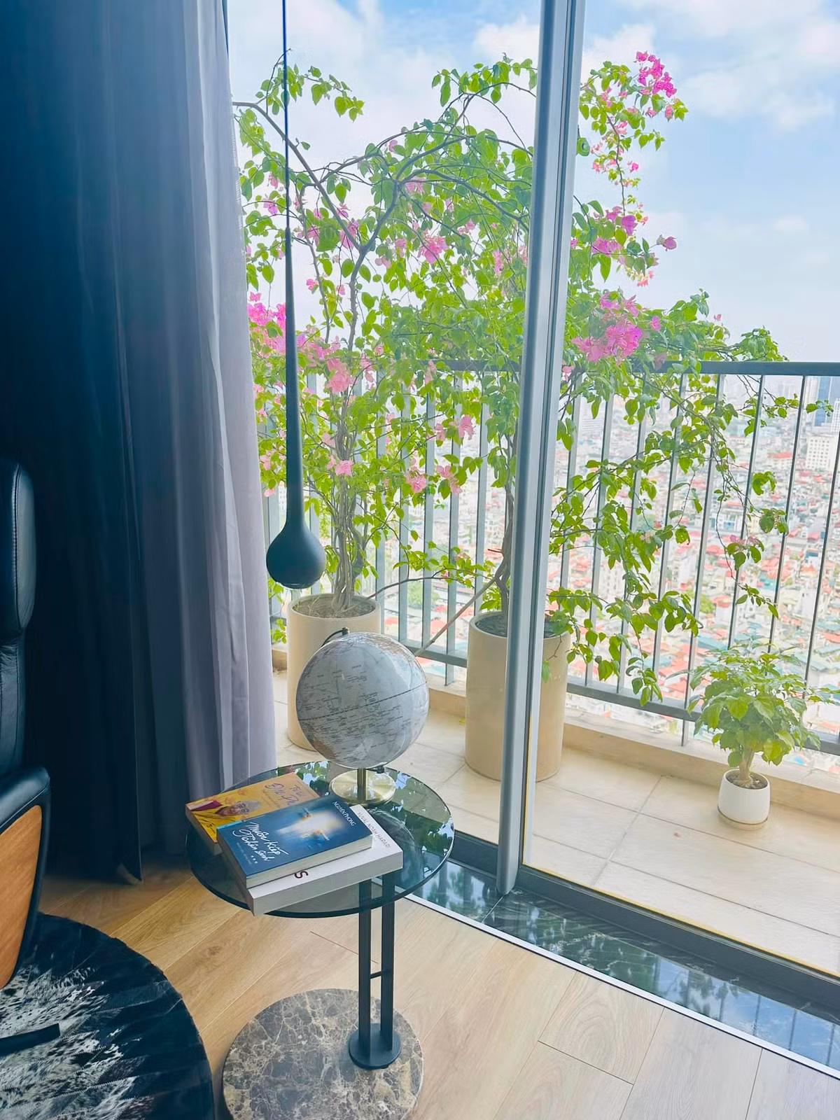 Góc đọc sách được bố trí cạnh ban công, ngập tràn ánh sáng. Bên ngoài ban công những chậu cây đang nở hoa rực rỡ.