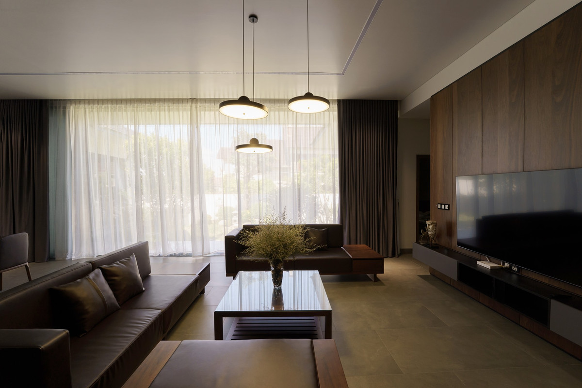 Bên trong, không gian sinh hoạt chung thoáng đãng nhờ hệ cửa sát trần. Nội thất hiện đại tông màu trầm kết hợp với hệ đèn vàng tạo cảm giác ấm cúng.