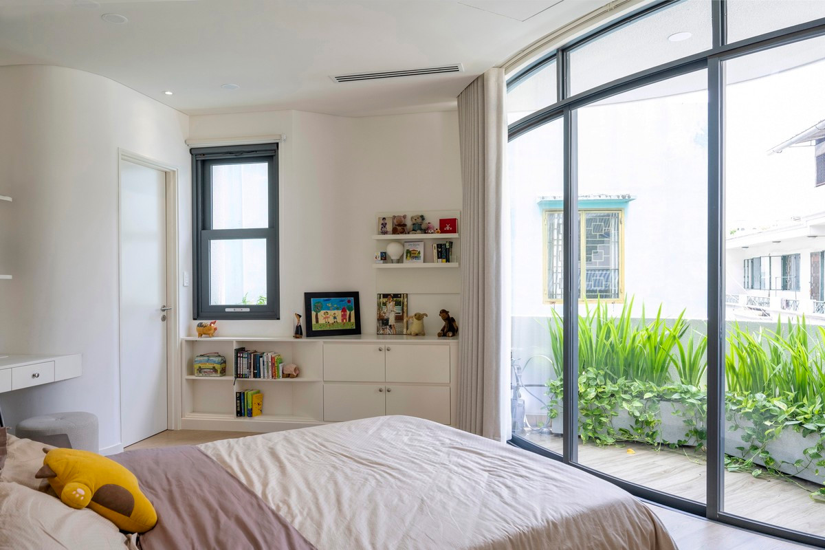 Phòng ngủ với hệ cửa sổ kính lớn tích hợp bồn cây được uốn cong bên dưới.