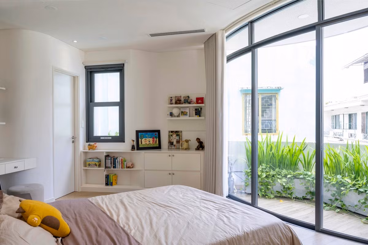 Phòng ngủ với hệ cửa sổ kính lớn tích hợp bồn cây được uốn cong bên dưới.