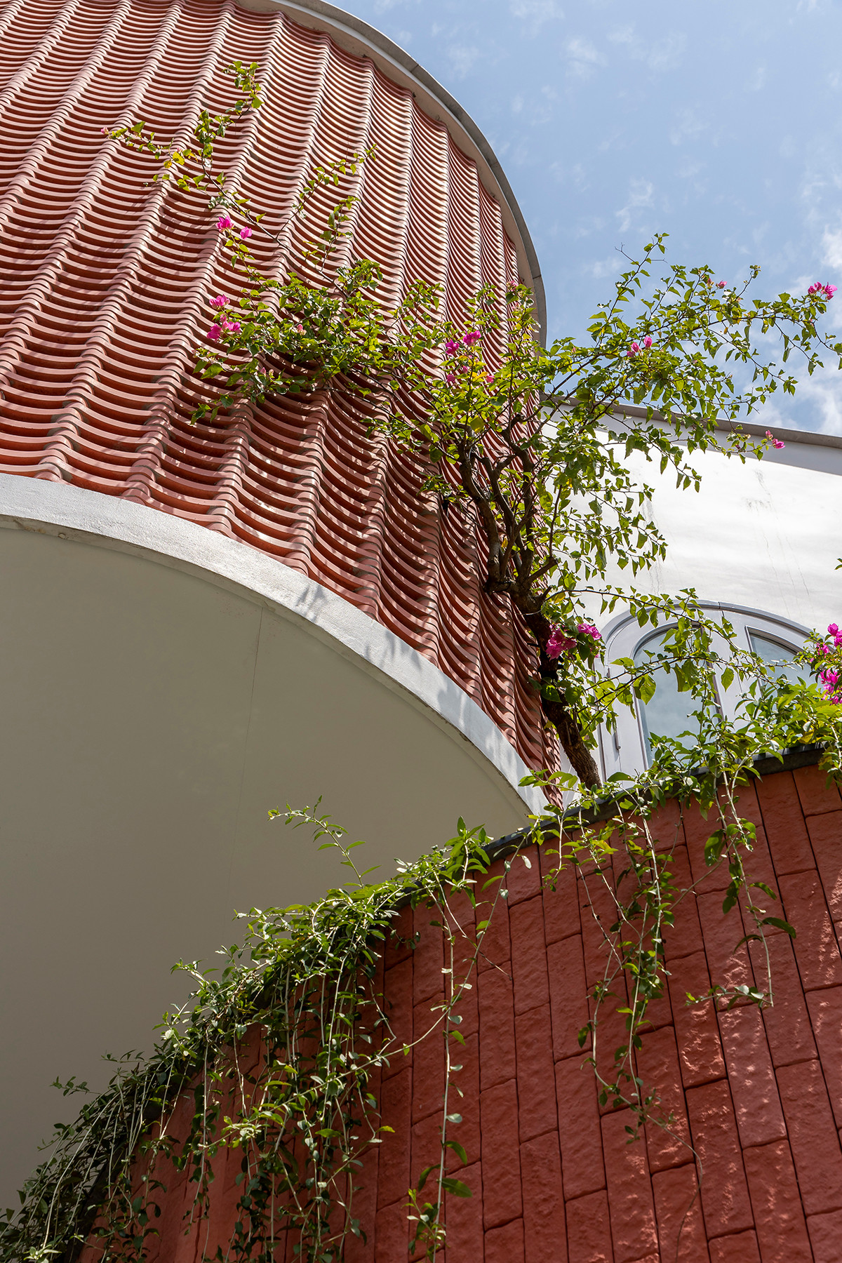 Một bức tường gạch được thiết kế ở mặt tiền, có tác dụng như lớp áo bao bọc lấy căn nhà. Cách làm này vừa giúp giảm bức xạ nhiệt vừa tạo không gian riêng tư.