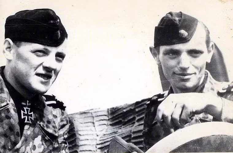 Bộ đôi Wittmann và Woll, được ví như tay và mắt trên chiếc Tiger của họ. Khả năng xác định và tiêu diệt mục tiêu của Woll được xem là độc nhất vô nhị trong Quân đội Đức khi đó. Và với Woll trên chiến trường không có bất kỳ giới hạn nào ngay cả khi đó là một mục tiêu di động. Woll chính thức trở thành chỉ huy xe tăng vào năm 1994 sau khi nhận huân chương Thập tự Hiệp sĩ vào cùng năm. Trong ảnh là Wittmann (bên trái) và Woll khi còn chiến đấu cùng nhau. Nguồn ảnh: blogspot.com.
