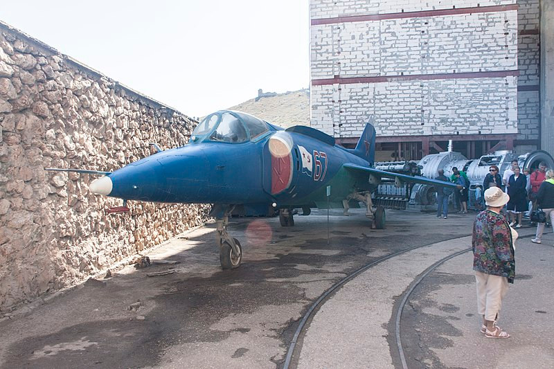 Máy bay tiêm kích cất hạ cánh thẳng đứng Yak-38 trưng bày trong khuôn viên căn cứ. Với khả năng cất – hạ cánh như trực thăng, Yak-38 có thể chiến đấu chỉ từ không gian rất nhỏ, phù hợp để phòng thủ căn cứ khi cần. Nguồn ảnh: Wikipedia