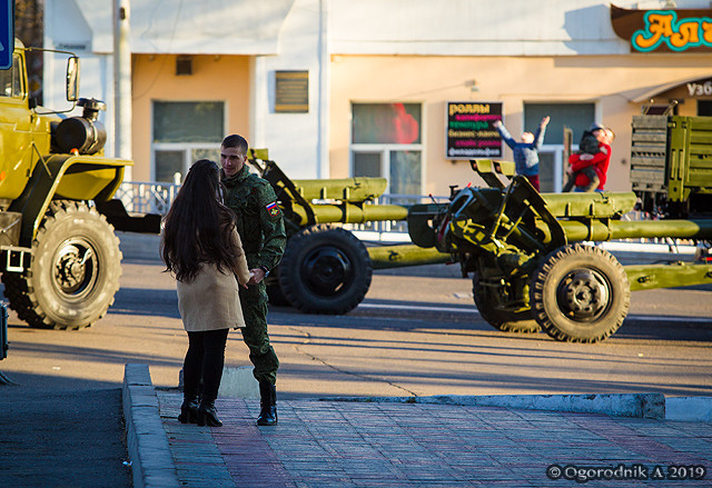 Một cặp tình nhân đứng cạnh đội hình xe kéo pháo – loại pháo đằng sau là D-30 122mm.