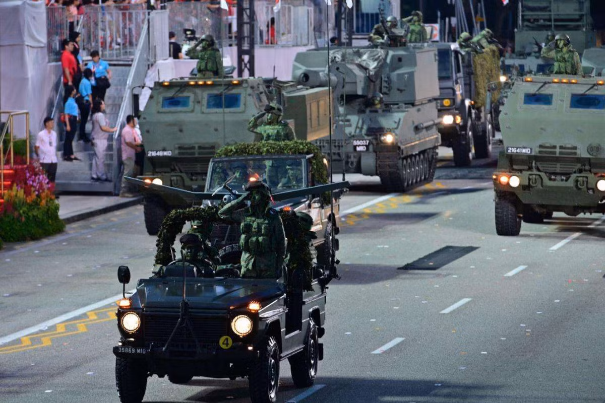 Xe SUV dẫn đầu đội hình các loại pháo hạng nặng hiện đại nhất Singapore gồm: pháo phản lực phóng loạt hạng nặng M142 HIMARS (đi đầu) và tiếp sau là pháo tự hành SSPH-1 Primus 155mm. Nguồn ảnh: Mediacorp