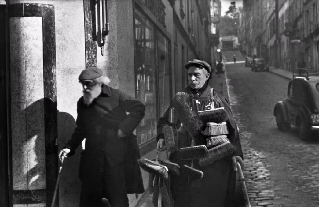 Người bán chổi với các sản phẩm treo trên người ở Montmartre, Paris, Pháp năm 1933. Ảnh chụp của Henri Cartier-Bresson.