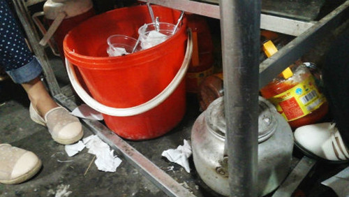 Dưới bàn ăn của quán ăn bình dân ngổn ngang đầy bát đĩa, giấy ăn. Thậm chí chai tương ớt cũng được tống xuống gầm bàn cạnh chân của khách hàng.