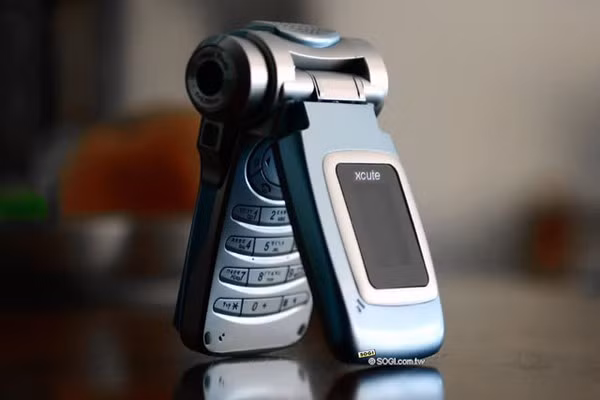  10. Xcute DV1 - Năm ra mắt: 2005. Xcute DV1 thực tế là một chiếc điện thoại khá sáng tạo với phần điều chỉnh camera được tích hợp vào cạnh máy. Dù vậy, do chưa được tối ưu về thiết kế, thiết bị này đã bị TechRadar đánh giá là một trong những chiếc điện thoại có thiết kế tệ nhất.