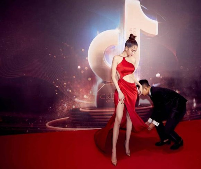 Đỗ Long cúi người chỉnh váy cho cô bạn thân tại sự kiện. Ảnh: Thương Hiệu và Pháp Luật.