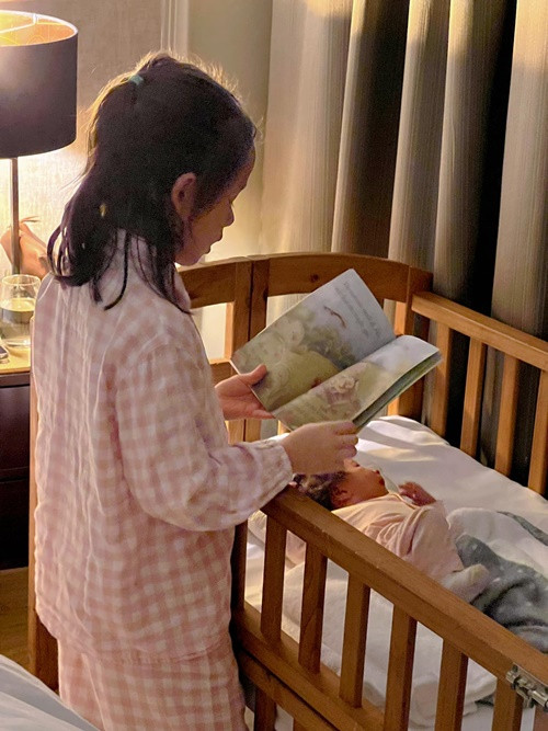 Bé Lina đọc truyện cho em gái trước khi ngủ.