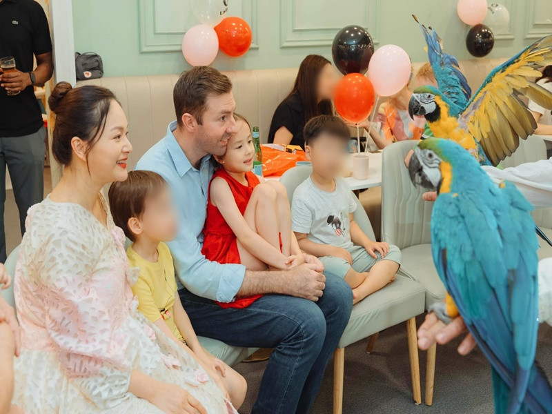 Bé Lina ngồi trong lòng bố xem những chú vẹt biểu diễn.