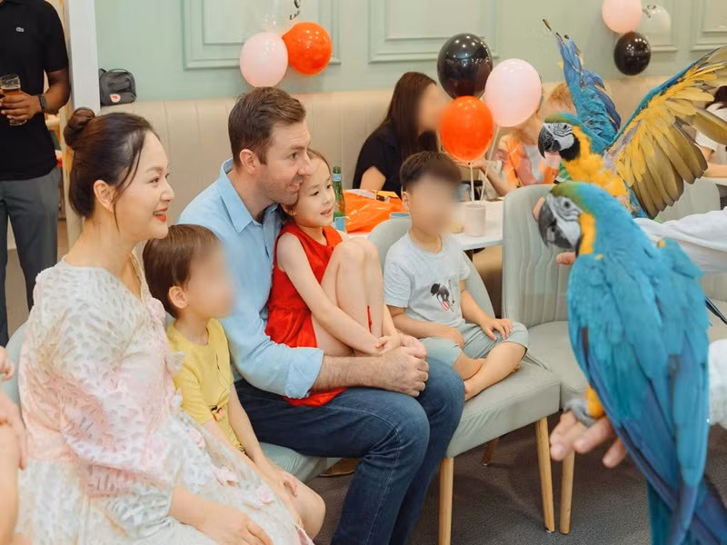 Bé Lina ngồi trong lòng bố xem những chú vẹt biểu diễn.