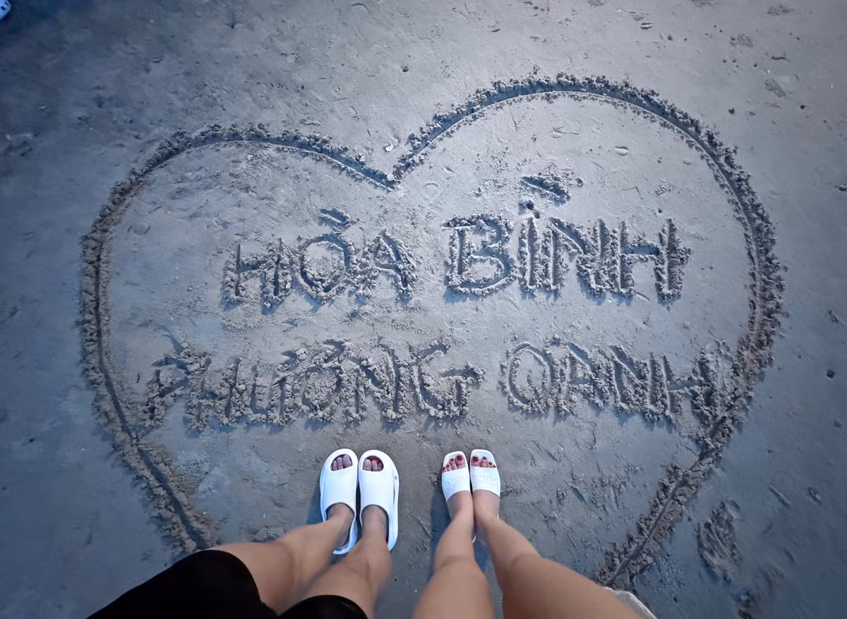 Cặp đôi cùng viết tên nhau lên cát.