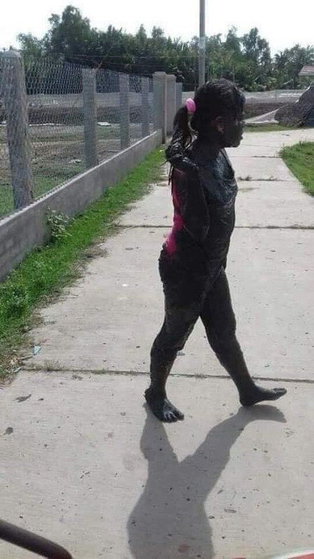 Riêng cô bé ngồi sau bị dính bùn đen từ tóc xuống chân. Chỉ có một mảng lưng áo và cái dây buộc tóc màu hồng là không bị bẩn.