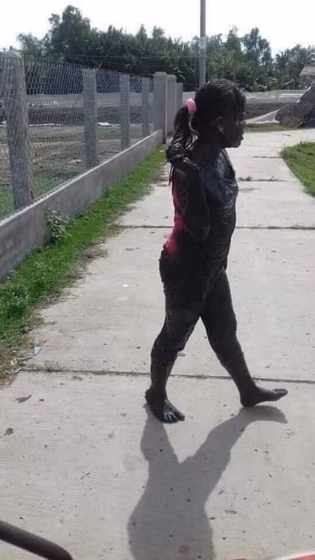 Riêng cô bé ngồi sau bị dính bùn đen từ tóc xuống chân. Chỉ có một mảng lưng áo và cái dây buộc tóc màu hồng là không bị bẩn.