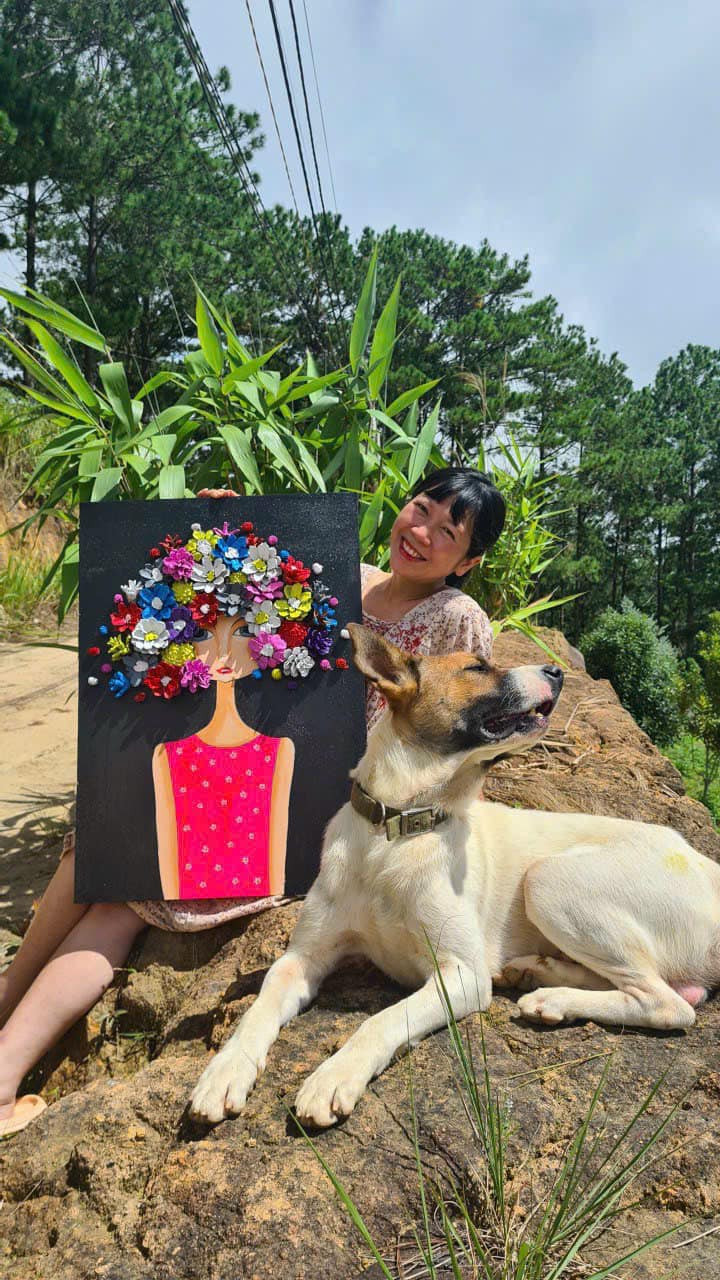 Hình ảnh cô gái tóc tém với nụ cười tỏa nắng ngồi cạnh chú chó cưng và bức tranh của mình khiến nhiều người cảm thấy rất dễ dịu và được truyền nguồn năng lượng tích cực. Ảnh: FBNV