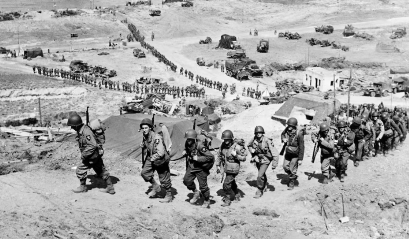 Quân tiếp viện của Mỹ hành quân lên một ngọn đồi ngang qua một boong-ke nhìn ra bãi biển Omaha gần Colleville sur Mer, Pháp, ngày 18/6/1944.