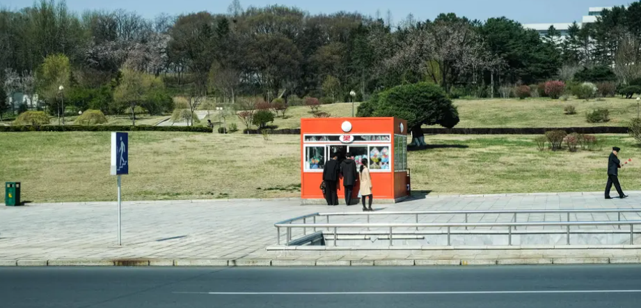 Người qua đường dừng lại mua đồ ăn nhẹ tại một ki-ốt ở trung tâm Bình Nhưỡng.