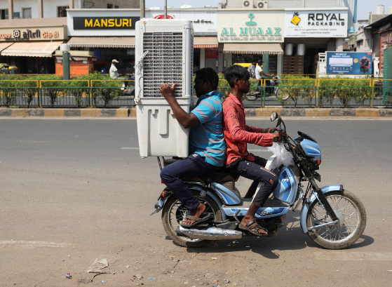 Những người đàn ông vận chuyển máy làm mát không khí bằng xe máy trong một ngày hè nóng nực ở Ahmedabad, Ấn Độ, ngày 20/5.