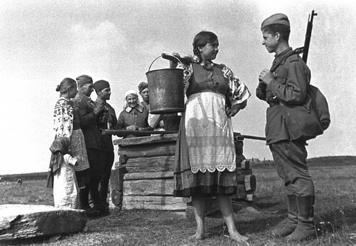 Người lính trò chuyện với cô gái cạnh giếng nước.