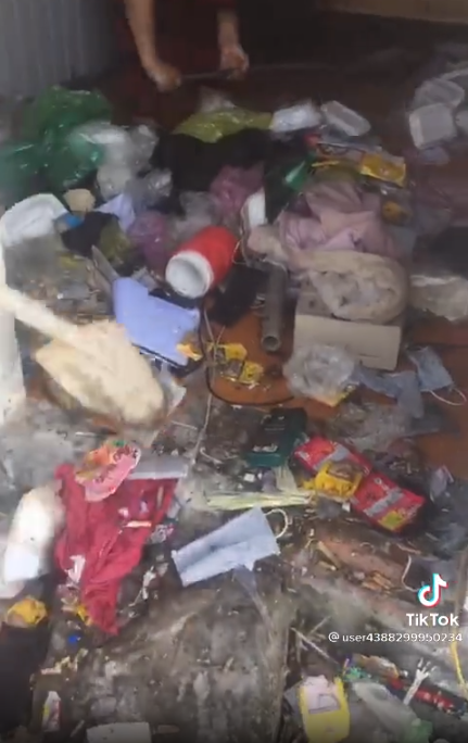 Đoạn video này cho thấy khung cảnh trong một căn phòng trọ bẩn, ngập trong rác thải, giấy vụn, vỏ bao thuốc lá, hộp đựng đồ ăn…