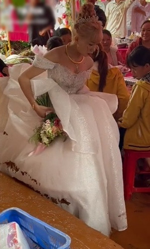 Theo đó, giống như bao cô dâu khác, nàng tân nương xinh đẹp cũng khoác lên mình bộ váy cưới trắng tinh khôi lộng lẫy trong đám cưới. Thế nhưng thay vì thuận lợi bước đi thì cô phải xách cao váy cưới, khó khăn di chuyển vì bên dưới toàn bùn đất khiến phần chân váy loang lổ vết bẩn.