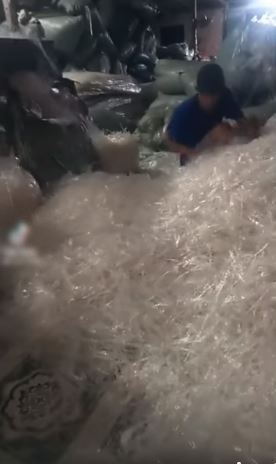 Hàng loạt các sợi bánh tráng được cắt nhỏ vụn rơi vãi khắp sàn nhà, thậm chí khi cho vào túi bóng to, các nhân viên ở đây còn dùng chân giẫm lên cho xẹp xuống.