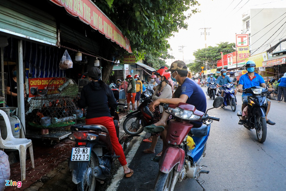 Trước một sạp bán thịt gia cầm, nhiều người đứng ngồi san sát chờ lấy hàng.