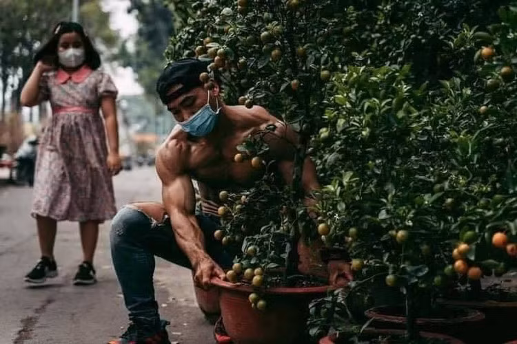 Điều đặc biệt đó là chàng trai 6 múi này nhìn lực lưỡng vậy nhưng cực kỳ chịu khó, vừa đứng ngoài vỉa hè chào mời bán quất cảnh vừa chăm chút, tưới nước cho từng chậu cây cực kỳ cẩn thận.