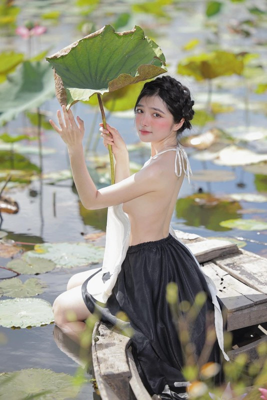 Khánh Linh diện áo yếm gam màu trắng, phối với chân váy đụp màu đen cùng kiểu tóc tết mô phỏng như khăn mỏ quạ.