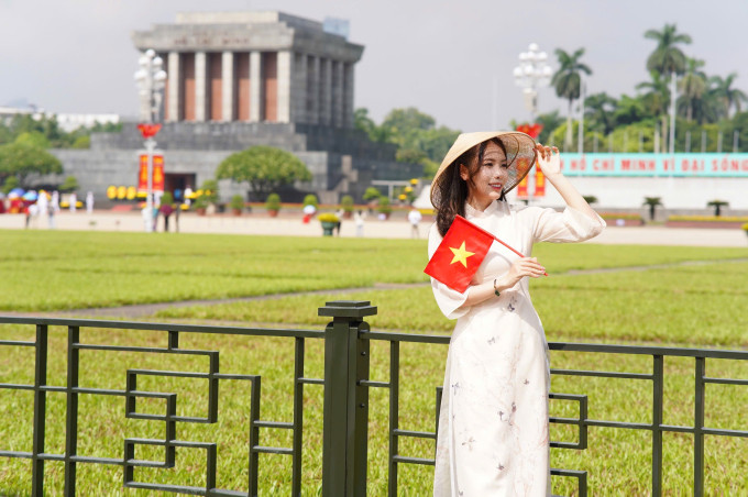 Nữ xạ thủ diện áo dài trắng thướt tha, đội nón lá và tay cầm lá cờ tổ quốc Việt Nam tự hào