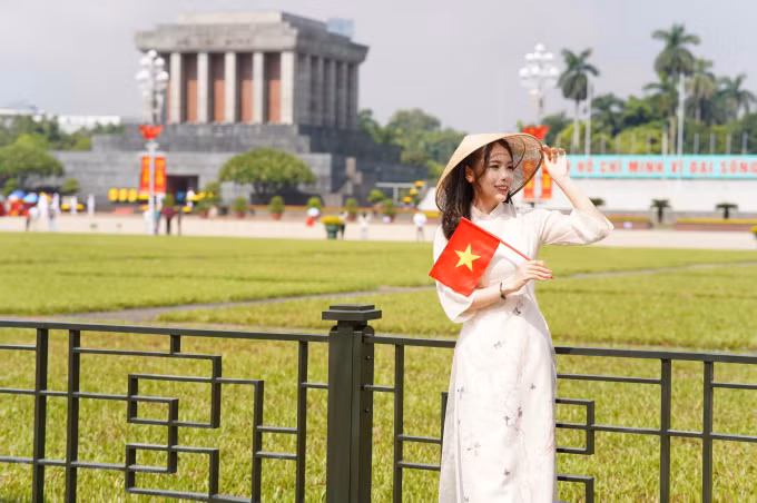 Nữ xạ thủ diện áo dài trắng thướt tha, đội nón lá và tay cầm lá cờ tổ quốc Việt Nam tự hào