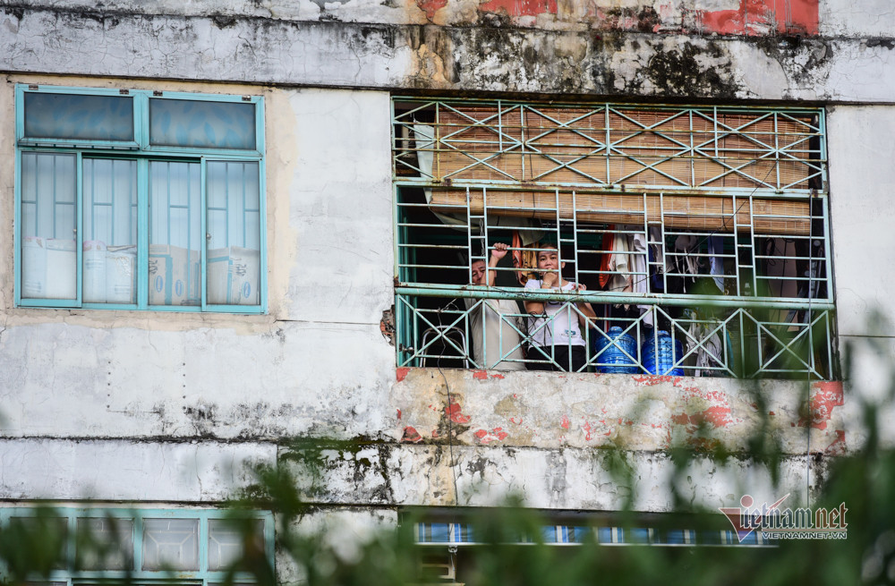 Một hộ gia đình nhìn ra khung cửa trong chung cư bị cách ly