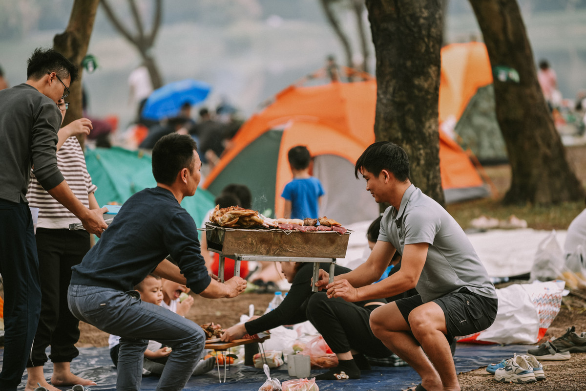 Các gia đình mang theo lều cắm trại, tự do thư giãn, tận hưởng bầu không khí thoáng đãng dưới rừng cây.