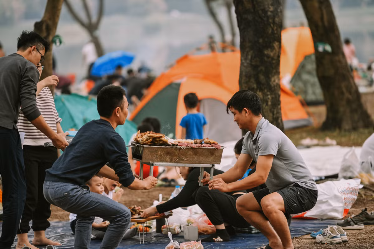 Các gia đình mang theo lều cắm trại, tự do thư giãn, tận hưởng bầu không khí thoáng đãng dưới rừng cây.