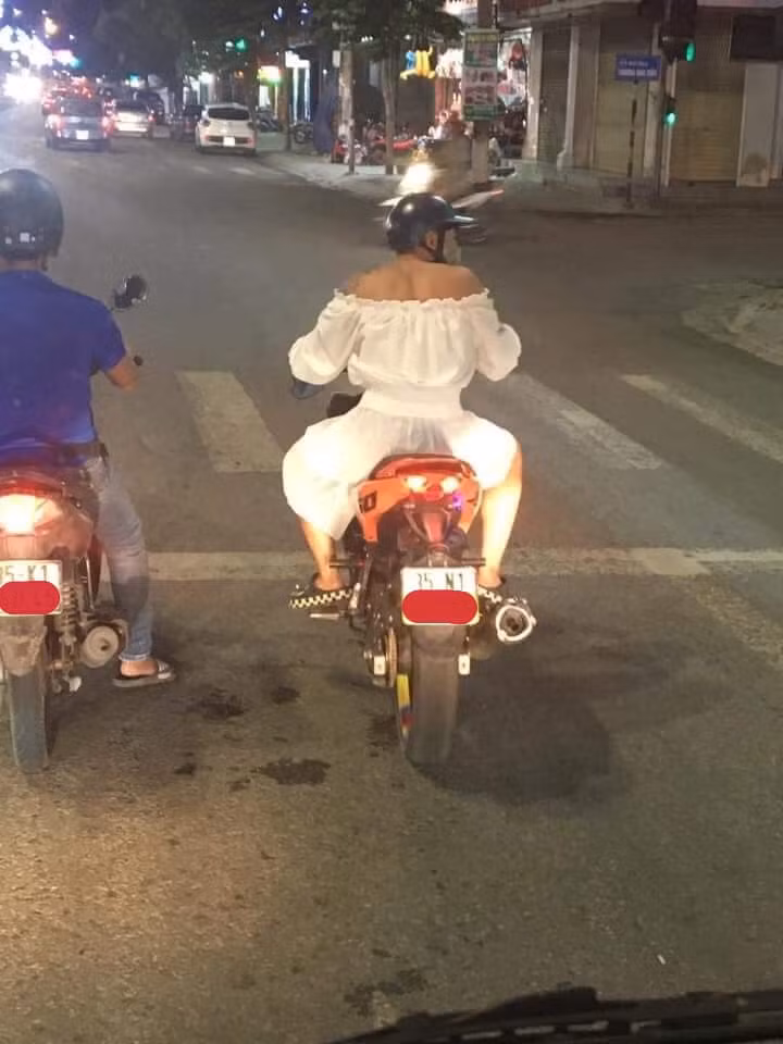 Cụ thể, trong bức ảnh được dân mạng chia sẻ một nam thanh niên diện váy trắng để lộ đôi vai cơ bắp cưỡi trên chiếc xe tay côn dừng đèn đỏ.
