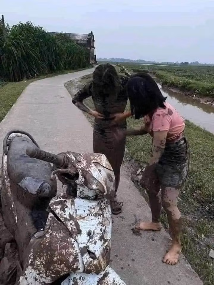 Cụ thể, xuất hiện trong hình ảnh ghi lại 2 cô gái đi chiếc xe máy màu trắng bị hư hại phần vỏ nhựa và đặc biết, người họ lấm lem toàn bùn, đất.