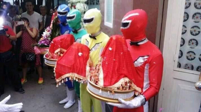 Trang phục vô cùng rực rỡ và phong phú, đủ các màu xanh, đỏ, vàng… Phía nhà gái là “siêu nhân nữ” điệu đà mặc thêm váy. Chưa kể, các thành viên còn nghịch ngợm tạo dáng đứng rất hài hước.