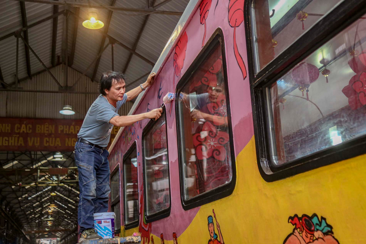 Công nhân của Xí nghiệp toa xe Hà Nội sơn bả lại phần cửa ra vào của toa tàu. Bên trong và ngoài toa được làm mới bằng màu sắc mang đậm không khí Tết với hàng chục bức họa phủ kín hai thành tàu.