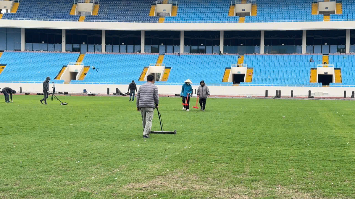 Các kĩ thuật viên dọn dẹp mặt cỏ sân Mỹ Đình nhưng vẫn còn rất nhiều vật để dính lại dưới.