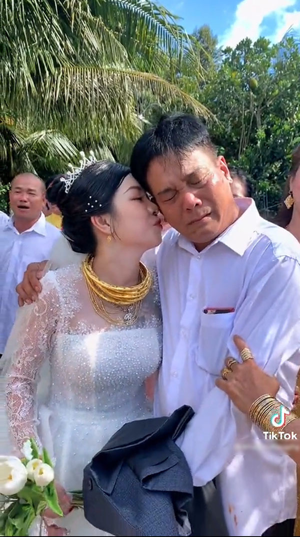 Đứng bên cạnh là cô dâu xinh đẹp đang bịn rịn bên bố. Khi thấy bố rưng rưng, mắt đỏ hoe thì cô gái đã dành tặng cho người bố của mình một cái thơm má để an ủi, mong bố đừng buồn nữa.