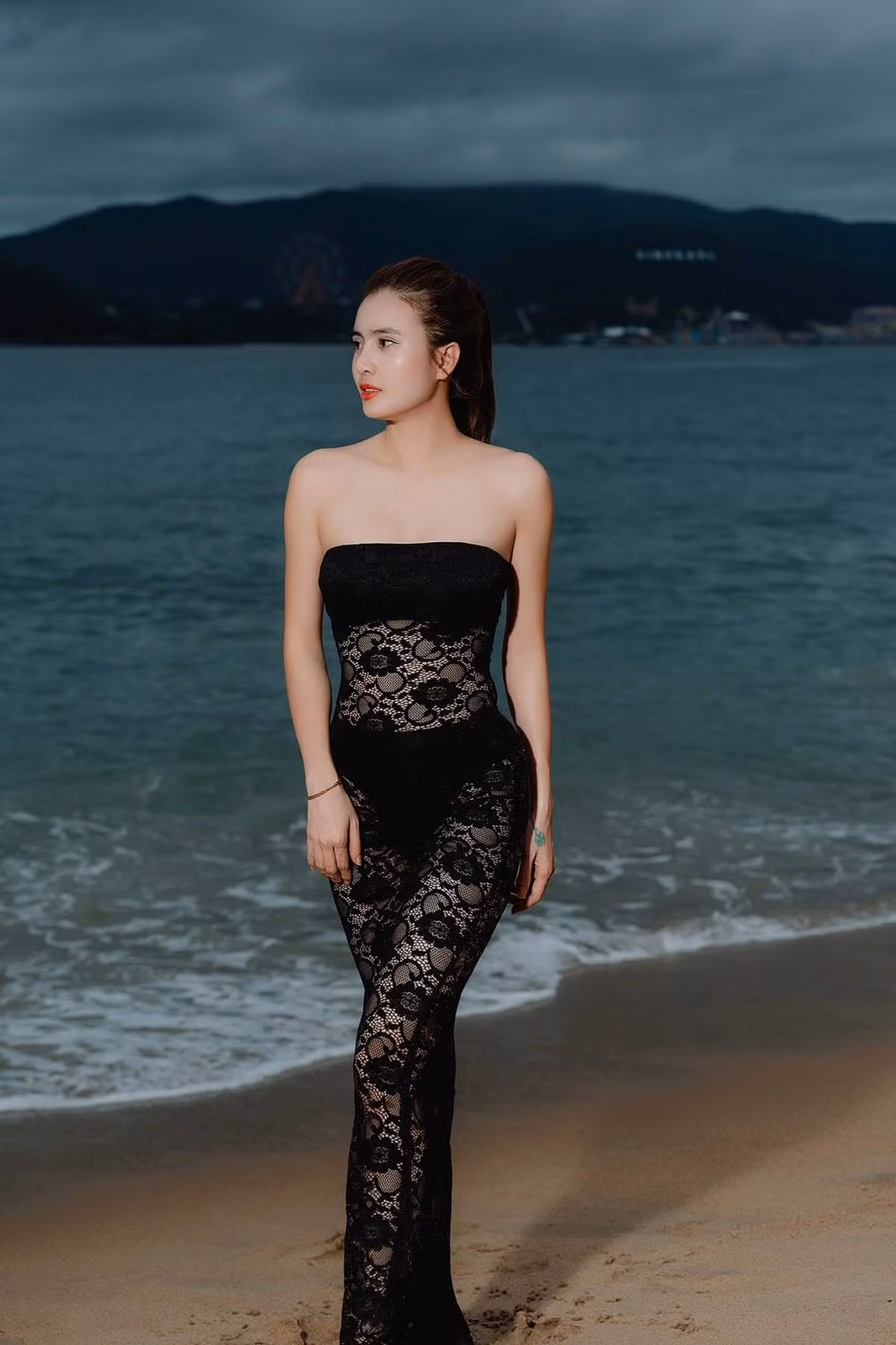 Thay vì mặc nguyên bộ bikini như những bức ảnh trước, lên này Khánh Chi diện chiếc đầm có họa tiết ren bó sát vào cơ thể làm tôn lên body quyến rũ của mình.