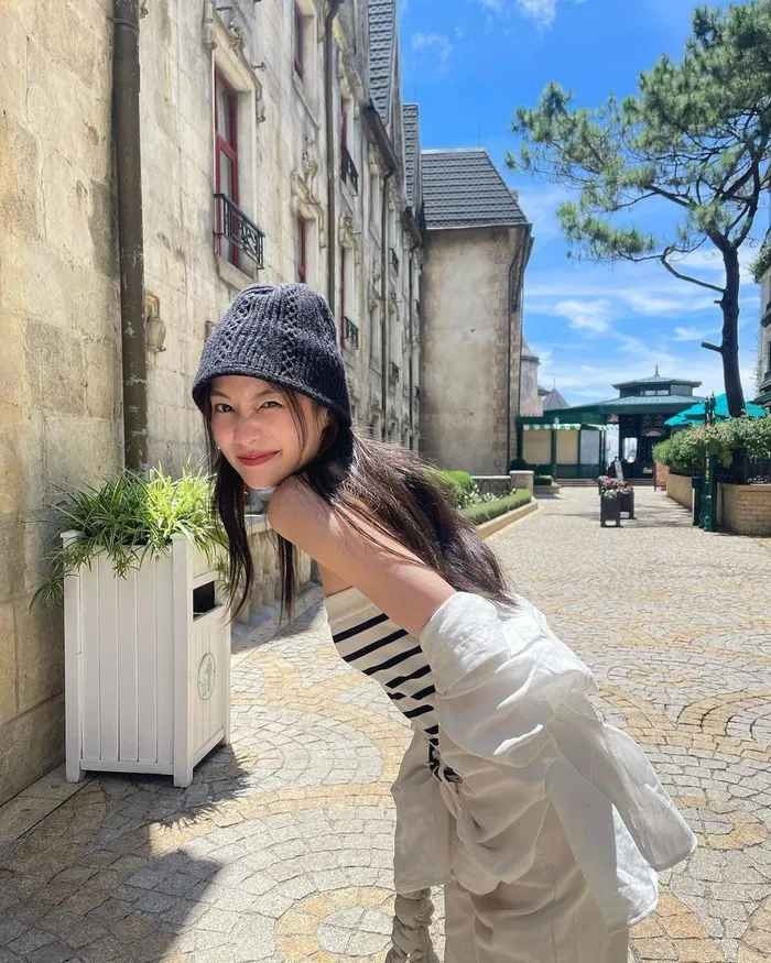 Đi thăm Bà Nà Hills vào ngày khá nắng, hot girl Thái Lan đã layer thêm 1 chiếc sơ mi oversize bên ngoài áo quây và đội thêm mũ len móc.